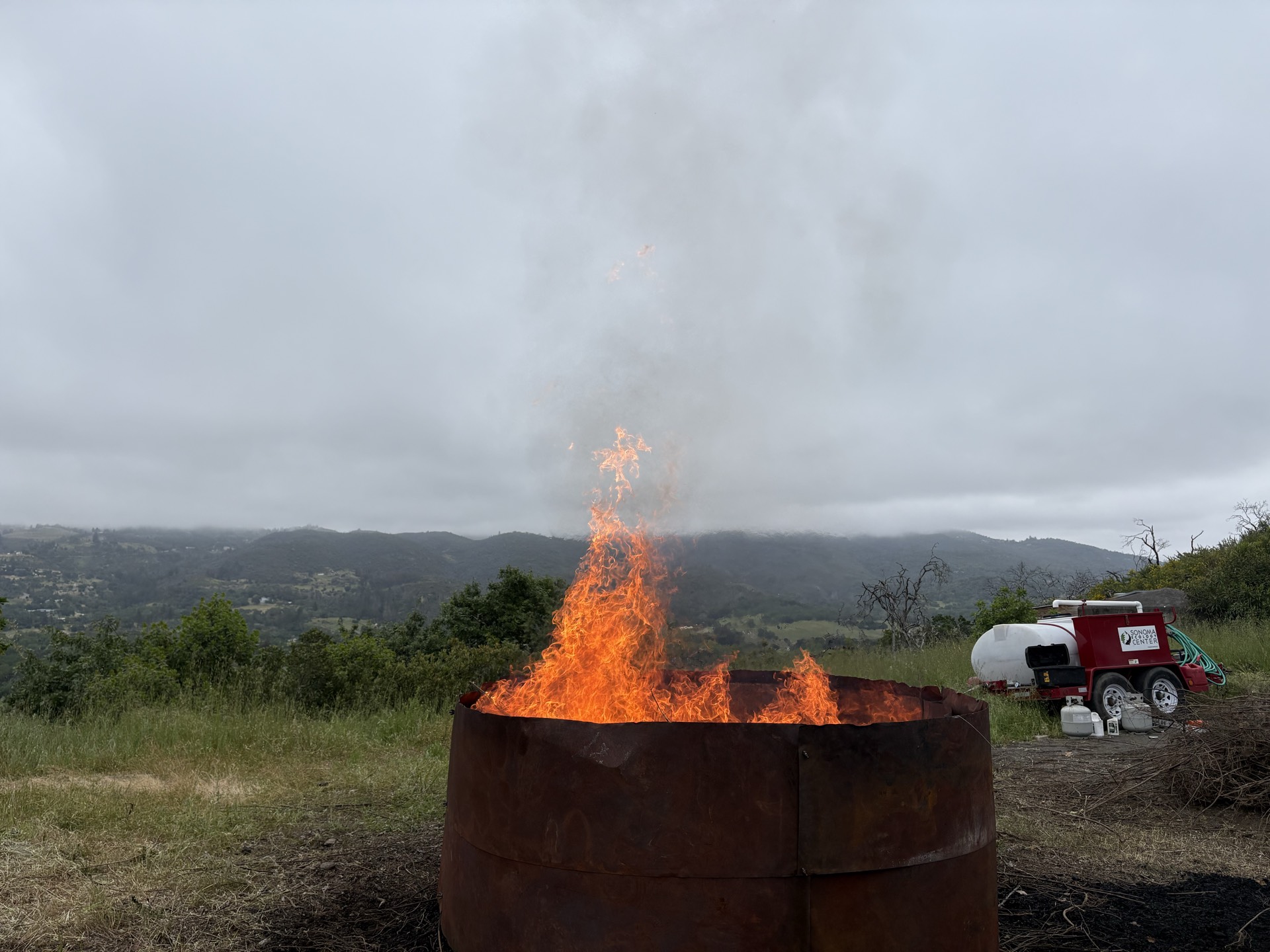Flame-cap kiln producing biochar on site above a Northern California valley